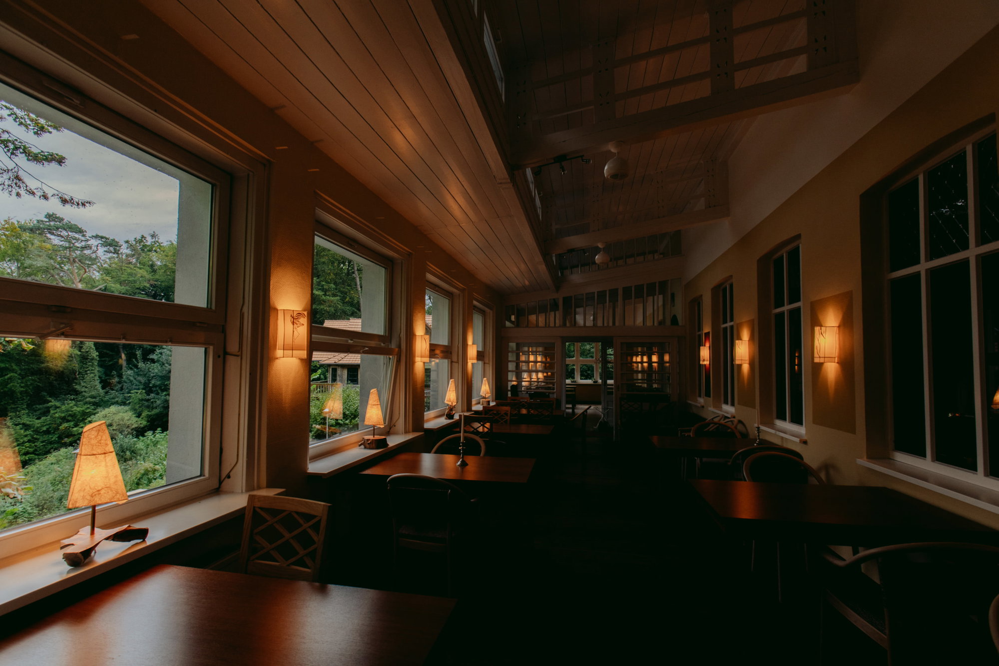 Warmly lit dining room with lake-facing windows at Haus am See Chorin